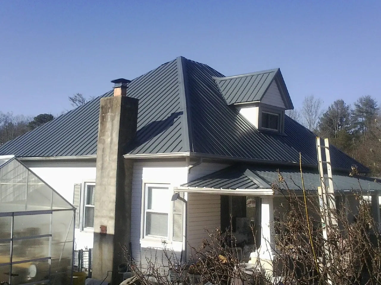 Dark blue standing seam metal roof on a white farmhouse with dormer — Slate & Tile Roof Repair by Roofing Brothers in West Stockbridge