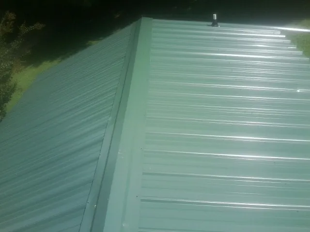 New green metal panels meeting at the ridge of a roof — Flat Roof Repair work by our crew in West Stockbridge
