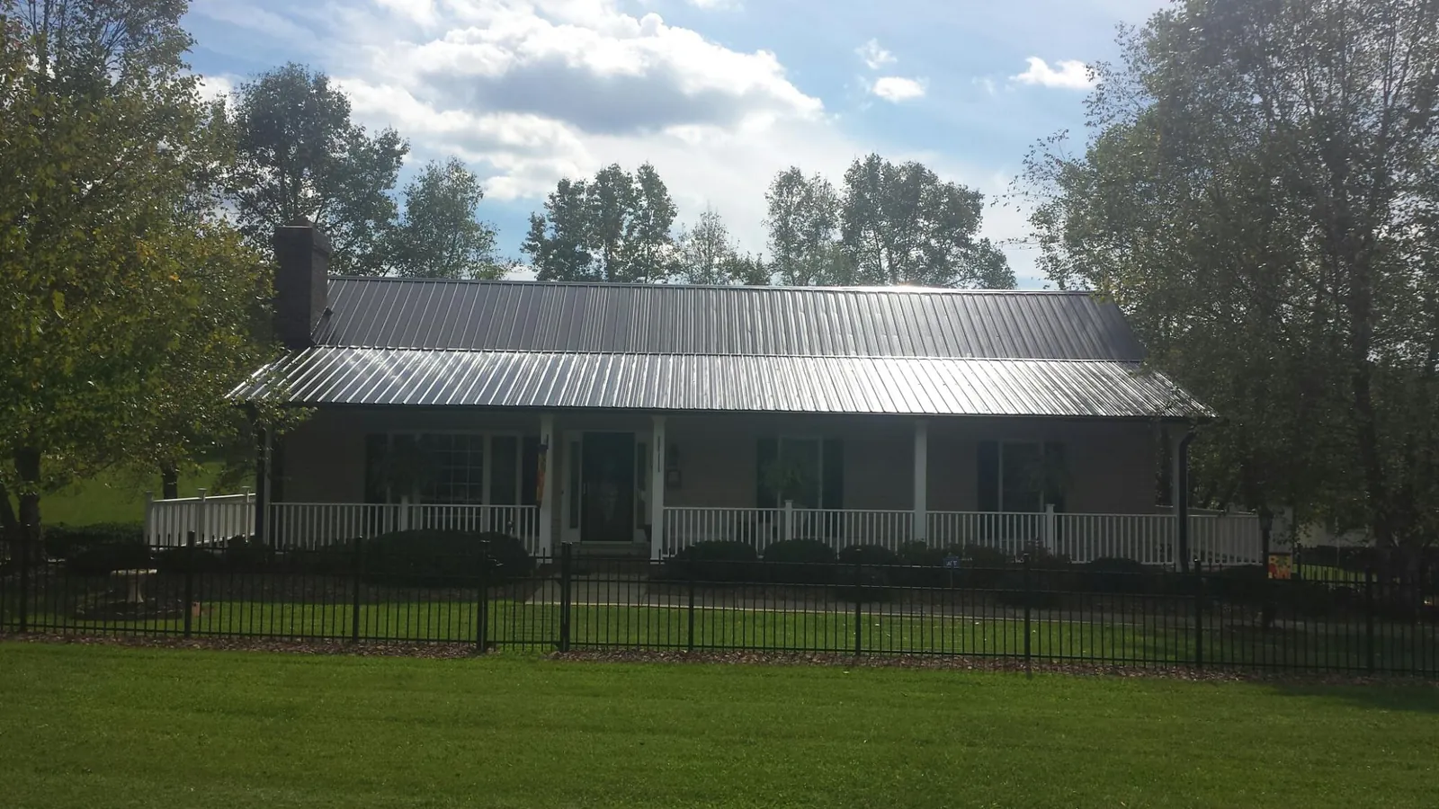 Gray metal roof on a brick ranch with a full width front porch — Gutter Guard Installation work by our crew in West Stockbridge