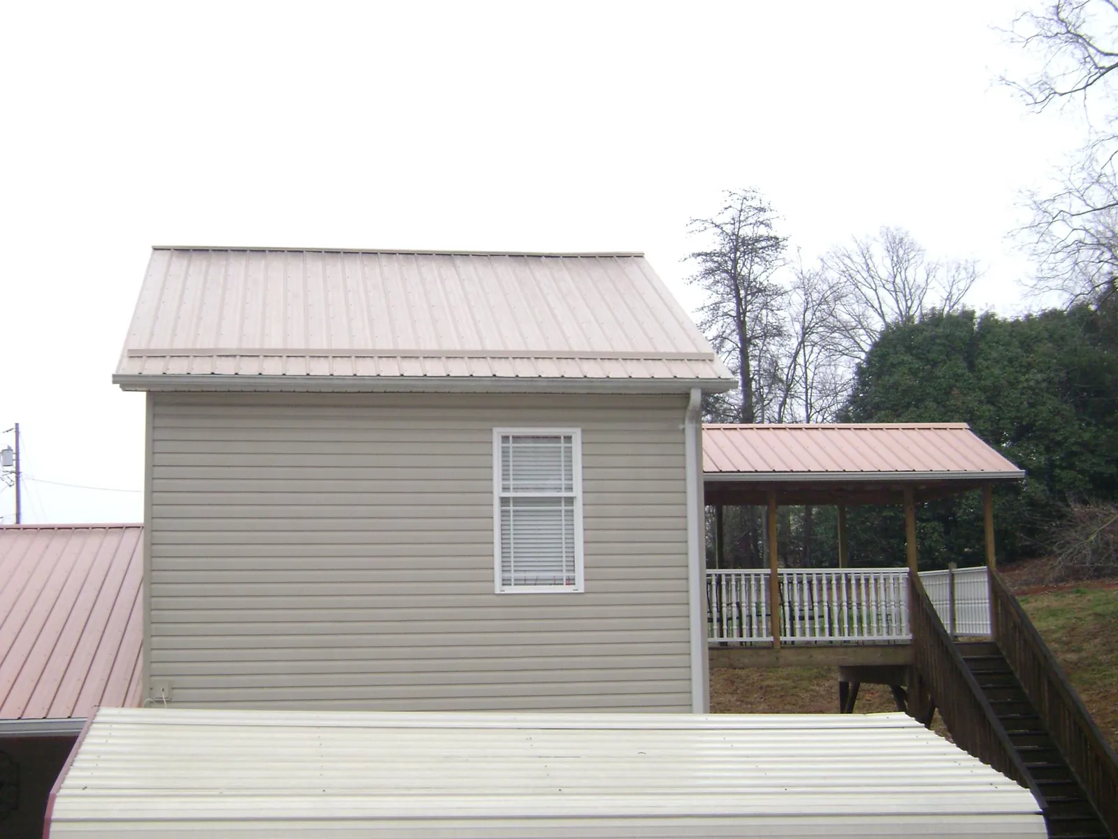 Tan metal roofs on a two story addition and attached porch, from a Roof Replacement job in West Stockbridge