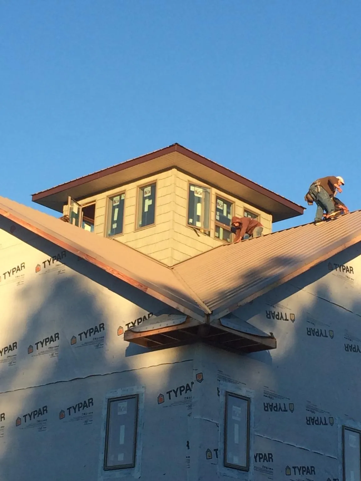 Roofers working around a rooftop cupola on a new metal roof at sunset — Roof Waterproofing in West Stockbridge by Roofing Brothers